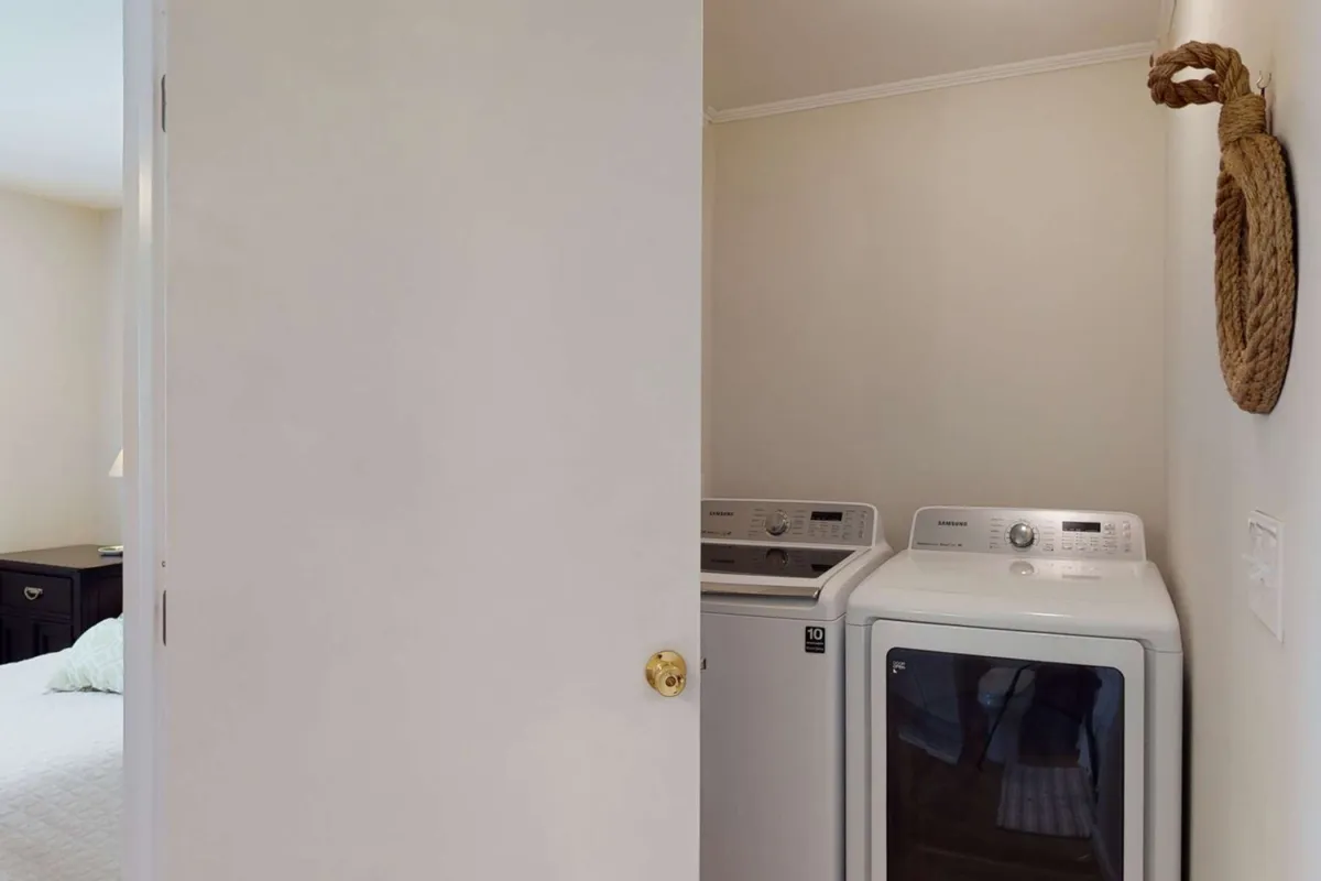 This image depicts a dedicated laundry area featuring a modern washing machine and dryer, conveniently located near a doorway. The scene is bright and practical, emphasizing the ease of doing laundry during your stay.